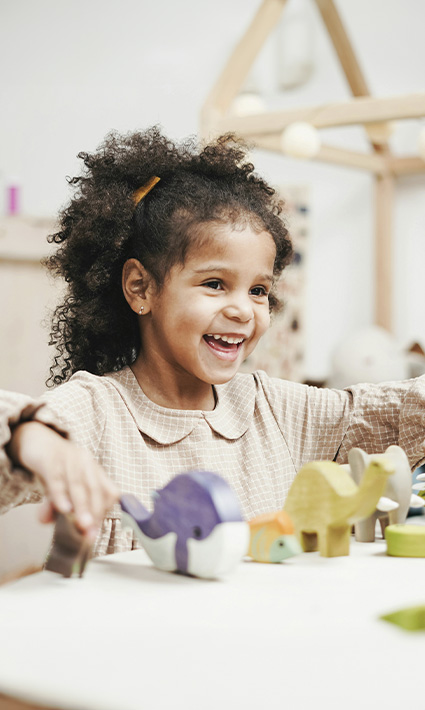 Little girl playing with toys and smiling in child therapy at Authentic Connections in Castle Rock, Colorado.