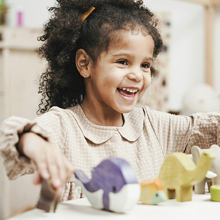 Little kid playing with toys and smiling in child therapy at Authentic Connections in Castle Rock, Colorado.