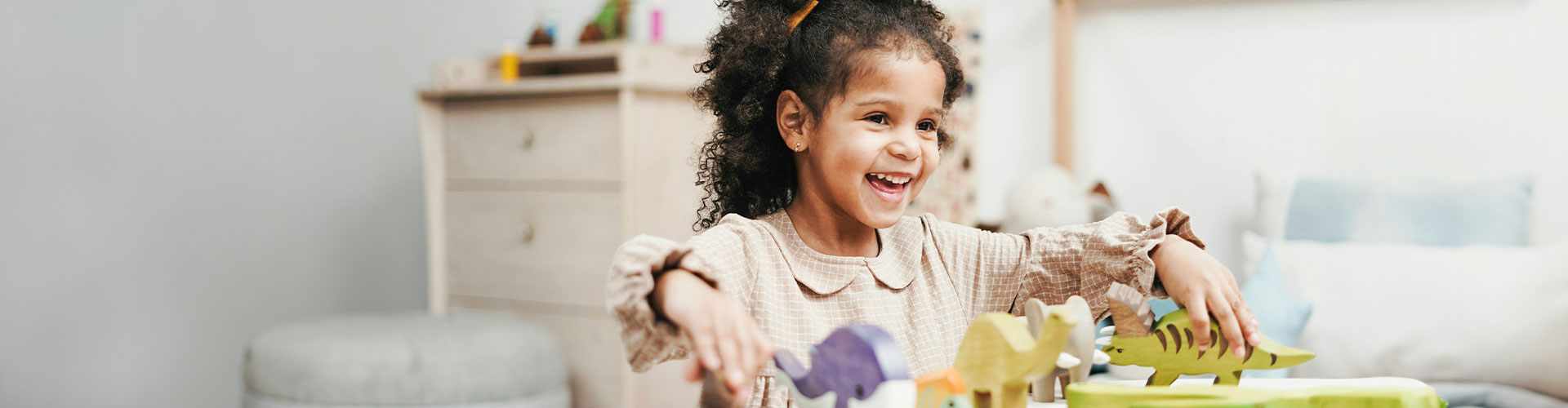 Little girl playing with toys and smiling in child therapy at Authentic Connections in Castle Rock, Colorado.
