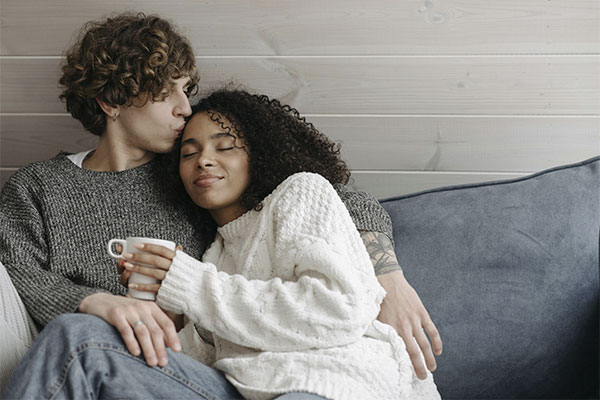 Man hugging and kissing his wife, their connection has strengthened with marriage counseling at Authentic Connections.