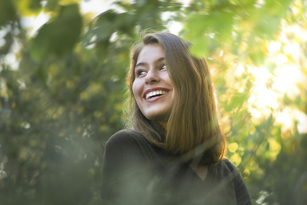 Women surrounded by light and nature with a happy and relaxed expression, suggesting the physical senses involved in EMDR.