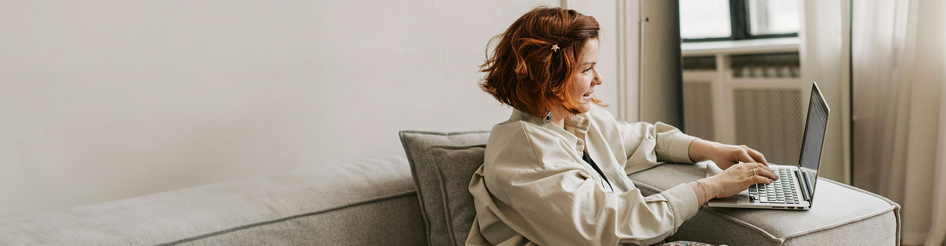 Woman sitting on the couch with a laptop, represents the positive effects of starting online therapy in Colorado.
