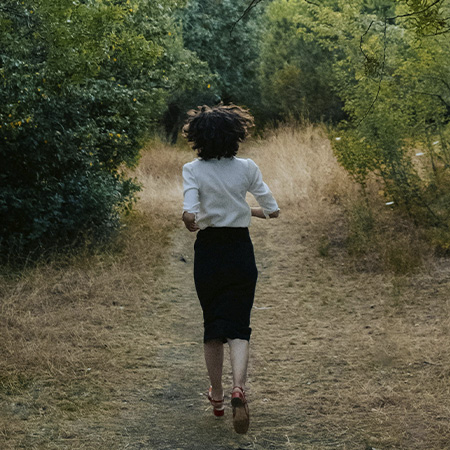 Woman in a forest, running from painful memories before starting trauma therapy & PTSD treatment in Castle Rock.