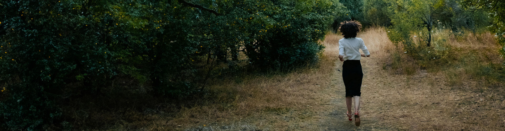Woman in a forest, running from painful memories before starting trauma therapy & PTSD treatment in Castle Rock.