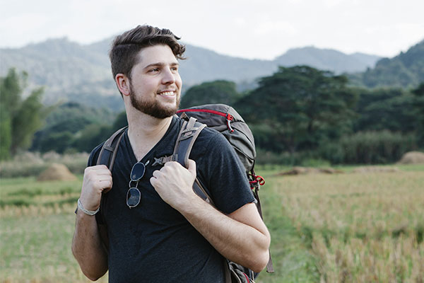 Young man walking in nature with a backpack starting his journey to improve his mental health and well-being.