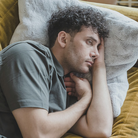 Man lying on the couch with a sad and worried expression, looking to start depression treatment in Castle Rock, CO.