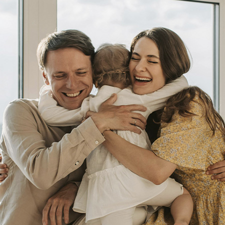 Couple hugging their adoptive daughter, a happy family after starting adoption counseling in Castle Rock, Colorado.