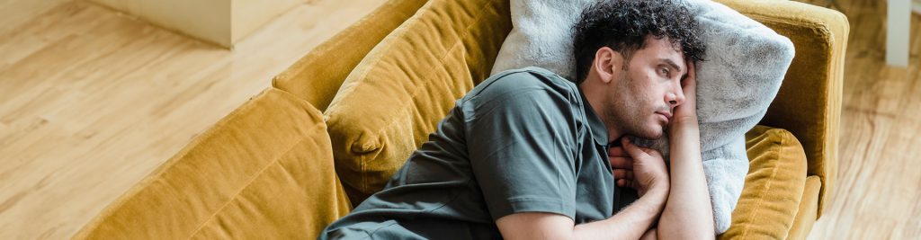 Man lying on the couch with a sad and worried expression, looking to start therapy for depression in Castle Rock, CO.