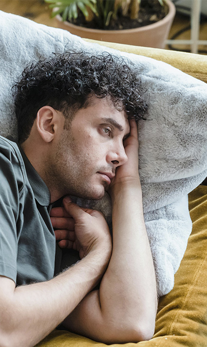 Man lying on the couch with a sad and worried expression, looking to start therapy for depression in Castle Rock, CO.