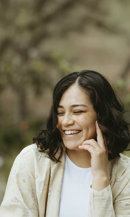 Woman smiling g surrounded by nature, represents how you can find relief fro pain through Brainspotting Therapy in Castle Rock, CO.