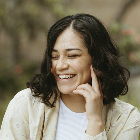 Woman smiling g surrounded by nature, represents how you can find relief fro pain through Brainspotting Therapy in Castle Rock, CO.